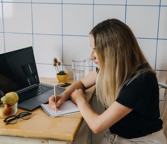 10-ből 4 fiatal mindössze 1 hónapig bírná jövedelem nélkül Shopping list, online Shopping, Save money. Young woman writing shopping list sitting near laptop at kitchen. Woman writing shopping list while sitting near notebook at home