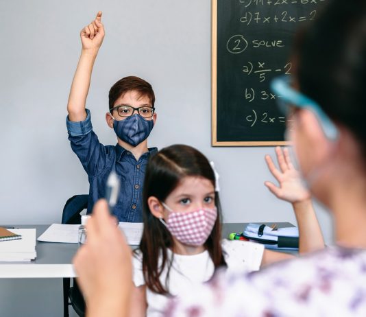 Hosszabb lockdown – kivéve az iskolák számára? Students with masks raising hands at school