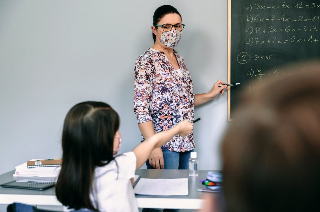 Digitális munkavégzést szorgalmaz a PDSZ valamennyi köznevelési intézményben és a szakképzés területén Teacher with mask explaining exercises in math class