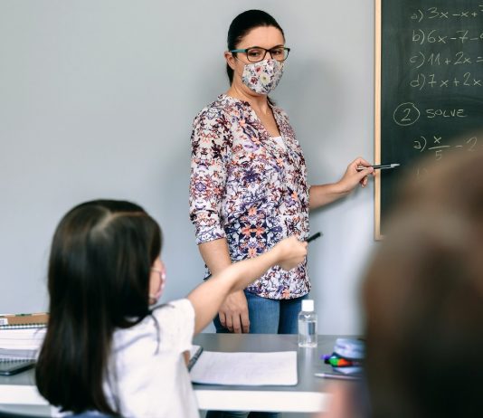 Digitális munkavégzést szorgalmaz a PDSZ valamennyi köznevelési intézményben és a szakképzés területén Teacher with mask explaining exercises in math class