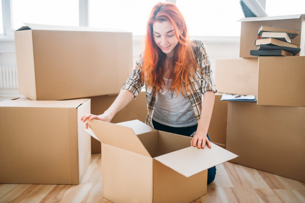 Woman unpacking cardboard boxes in new home