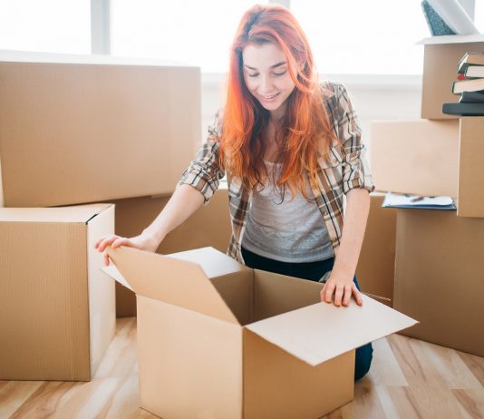 A lakhatási támogatás segítheti a távoli munkavégzést Woman unpacking cardboard boxes in new home