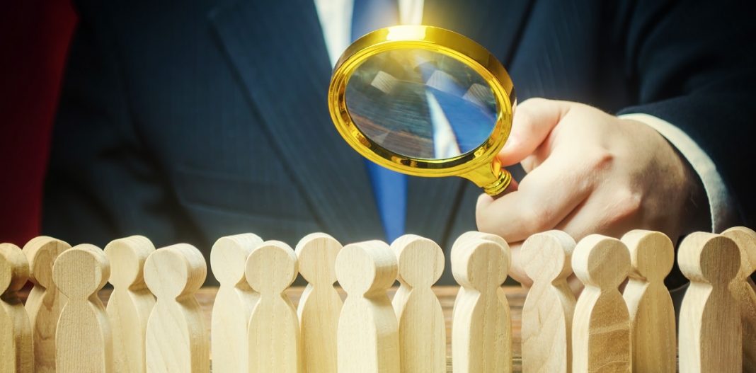 Businessman is studying a crowd of people with a magnifying glass. Hr search candidates for work, staff recruiting. Society, demographic. Market and customers research. Citizens electorate. Analysis