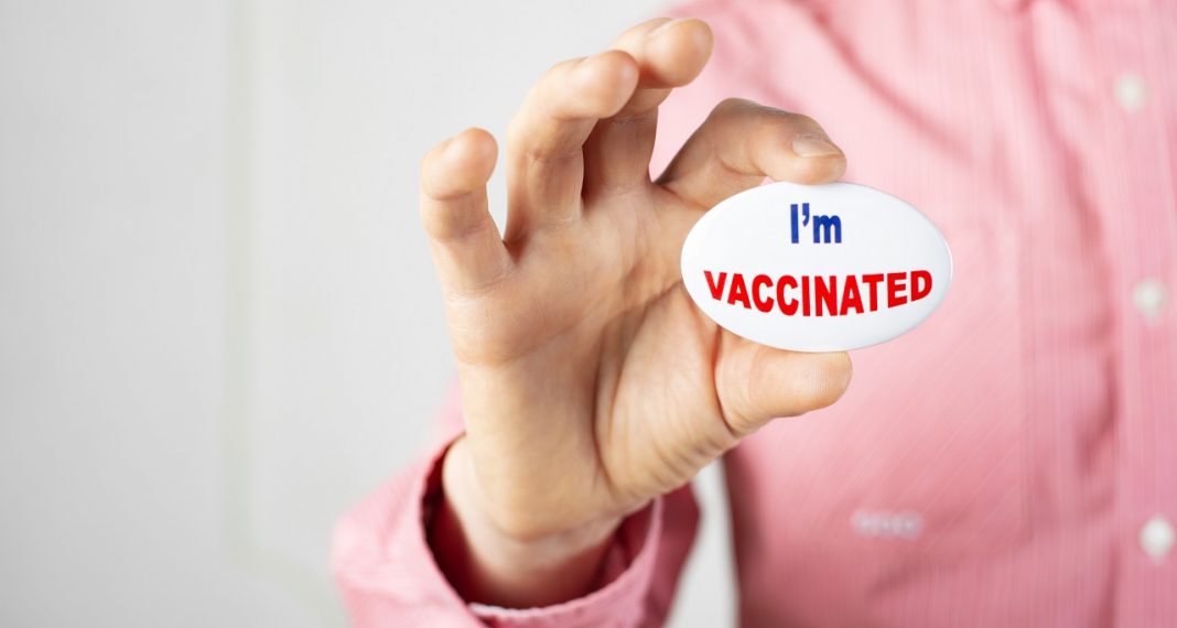 Vaccination campaign button pin in caucasian male fingers. Copy-
