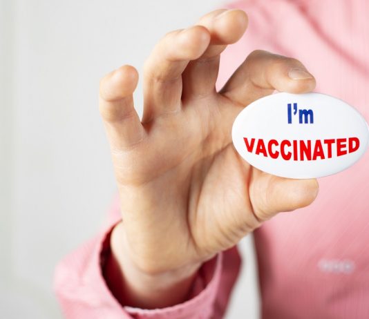 Ma véglegesíthetik az újranyitás kérdéseit Vaccination campaign button pin in caucasian male fingers. Copy-