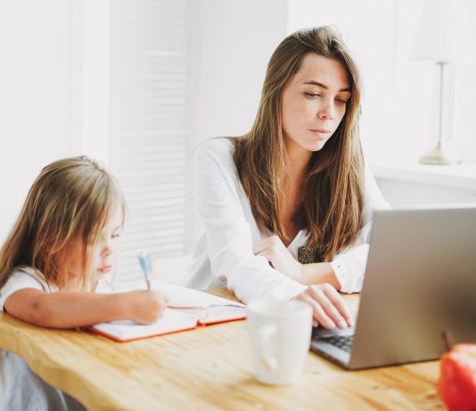 Újabb három hónapig egyszerűbb távmunkában dolgozni Working mom freelancer on the laptop with little daughter drawing on the table at home
