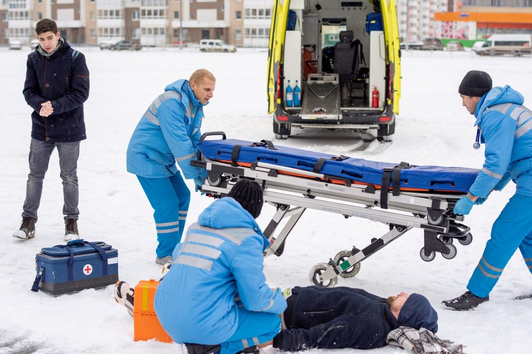 Több odafigyelésre és plusz intézkedésekre van szükség a munkavédelemben a hideg idő miatt Brigade of young paramedics in workwear preparing stretcher for unconscious man