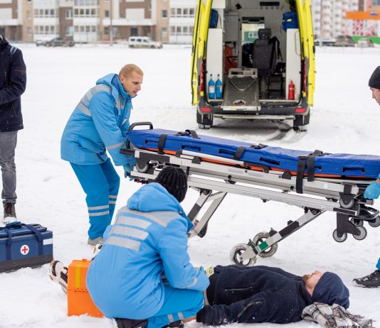 Több odafigyelésre és plusz intézkedésekre van szükség a munkavédelemben a hideg idő miatt Brigade of young paramedics in workwear preparing stretcher for unconscious man