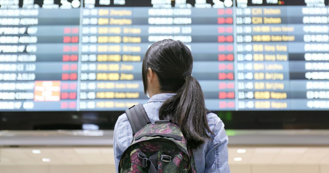 Young woman traveler looking for the flight number number at airport