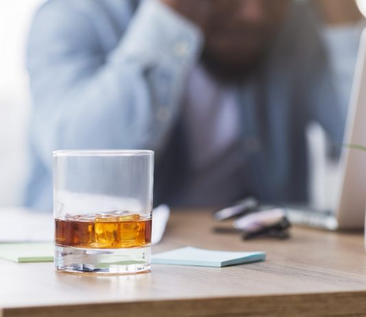 A németek többet isznak a koronavírus-járvány alatt Desperate black businessman suffering from bankruptcy, drinking alcohol at workplace.