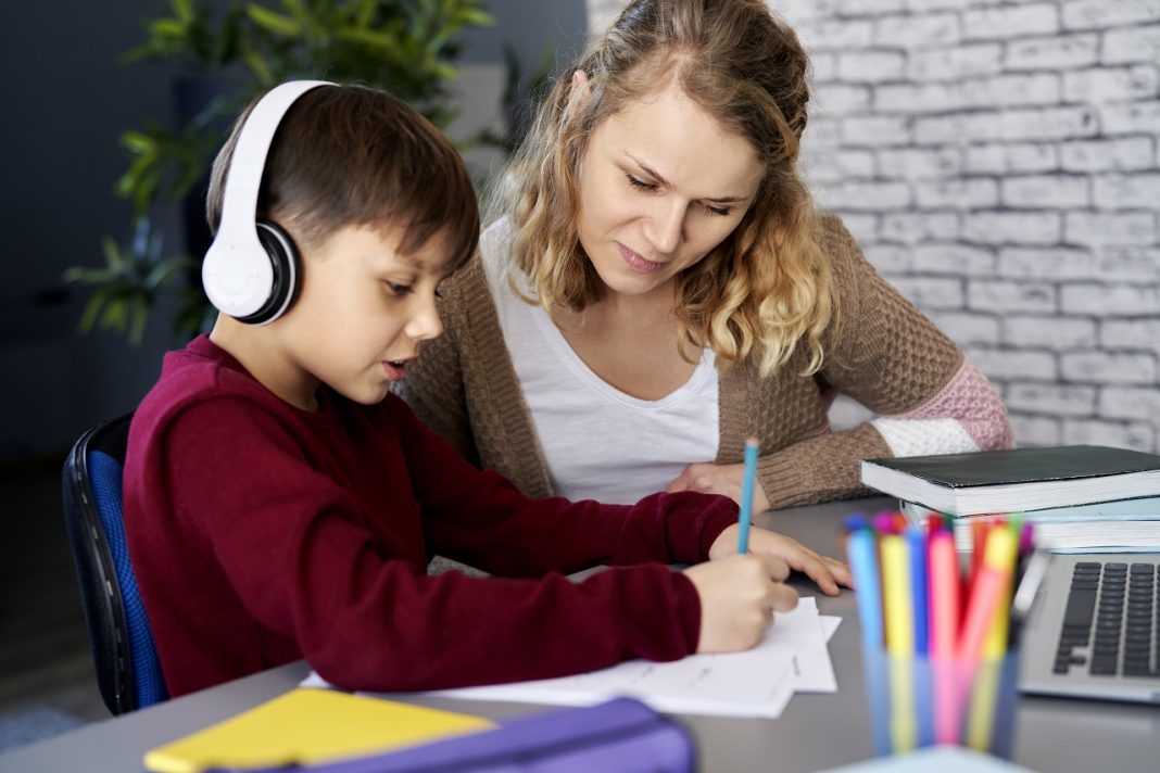 Home office gyerekekkel – az utópia és az önszervezés között Boy happily doing homework with his mom at home