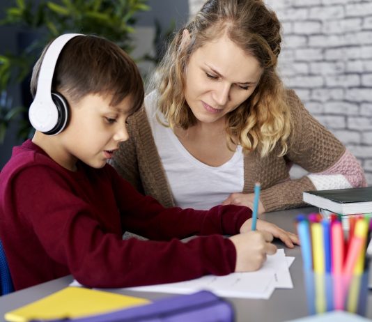 Home office gyerekekkel – az utópia és az önszervezés között Boy happily doing homework with his mom at home