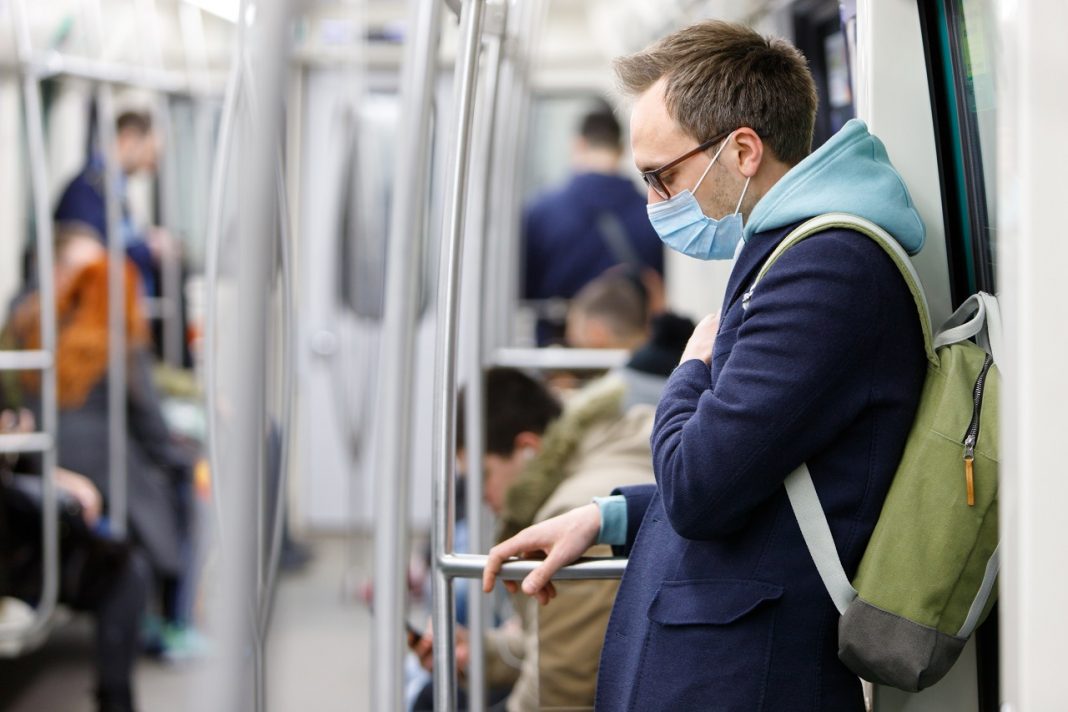 Ill man feeling sick, wearing protective mask in public transpor