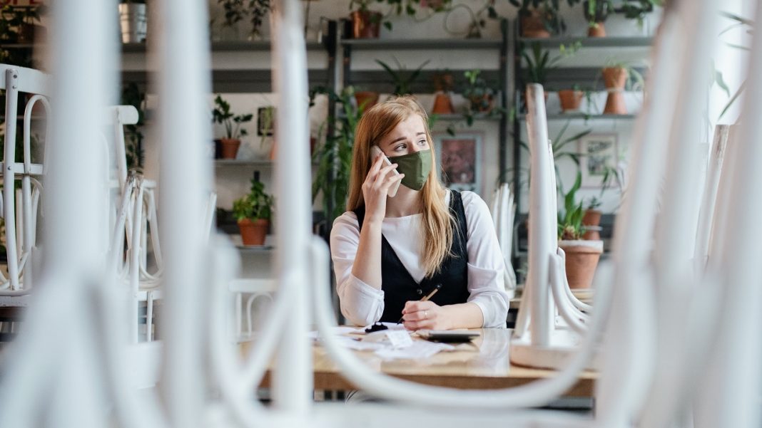 A munkanélküliek ötöde fiatal Frustrated owner sitting at table in closed cafe, small business lockdown due to coronavirus.
