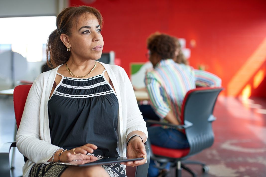 Hogyan támogathatják a férfiak a női vállalkozókat? Confident female boss working on a digital tablet in red creative office space