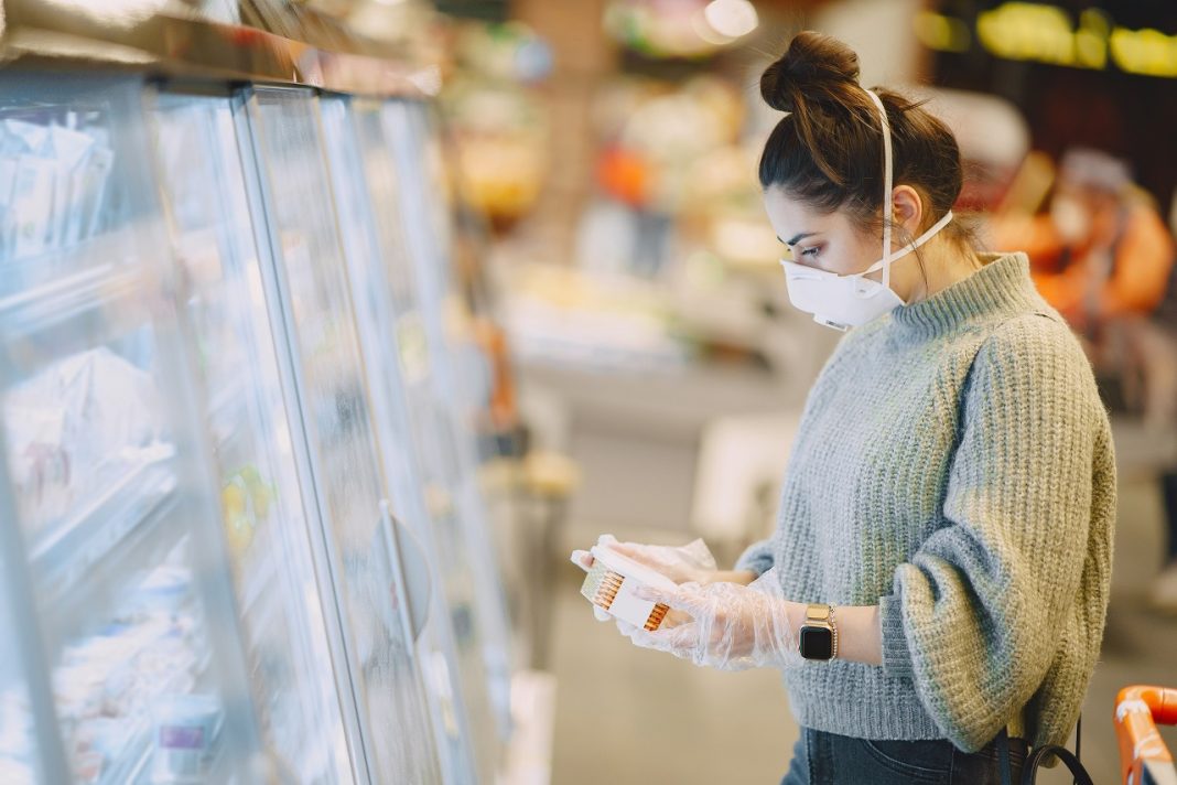 Az üzletek online továbbra is nyitva tarthatnak Woman in a respirator in a supermarket