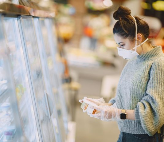 Az üzletek online továbbra is nyitva tarthatnak Woman in a respirator in a supermarket