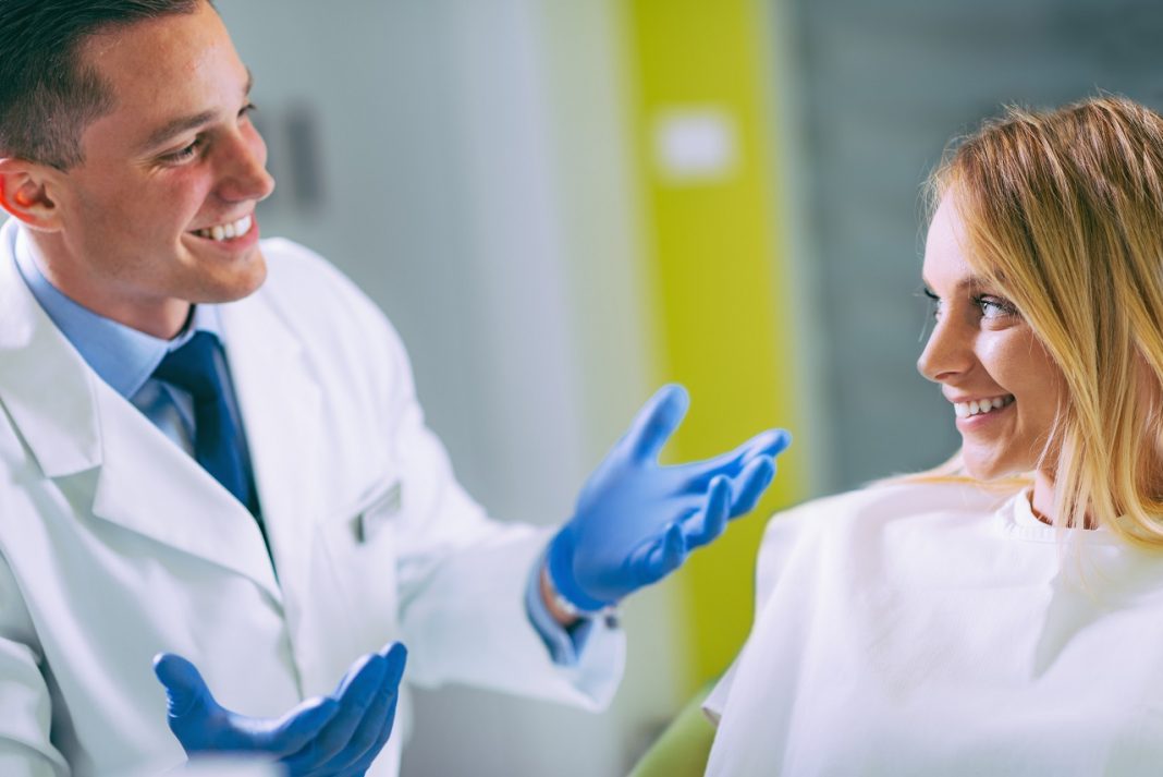 oung Dentist Talking to Satisfied Patient