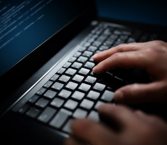 Kibervédelmi intézet: a Magyar Posta arculati elemeit használják adathalászok Programmer or computer hacker typing on laptop keyboard