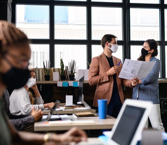 Jogszerű felmondási ok lehet-e a vírussal szembeni szkepticizmus? – Kirúgható-e a vírustagadó kolléga? Portrait of young businesspeople with face masks working indoors in office.