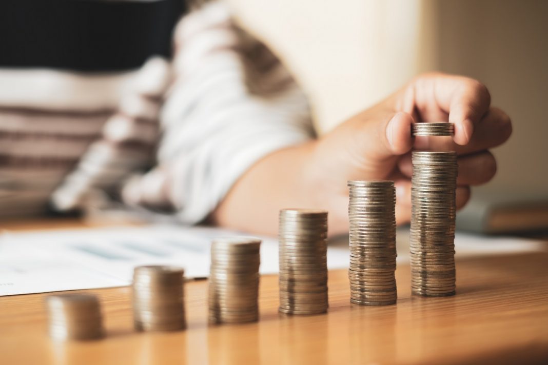 Woman's hand. Place a coin on the coin graph with coins, saving
