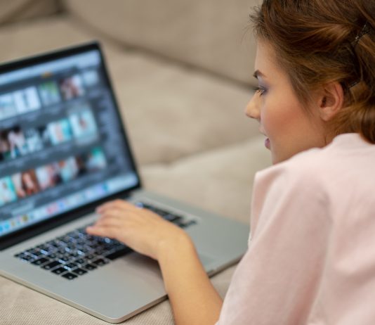 Jogszerűen ellenőrzi-e a munkavállalók saját számítógépeit a munkáltató? Attractive woman with laptop at home.