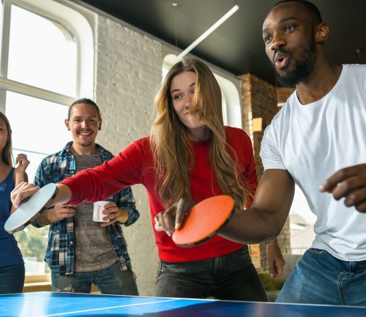 Legyen egészségtudatosabb a munkahelyekre való visszatérés Young people playing table tennis in workplace, having fun