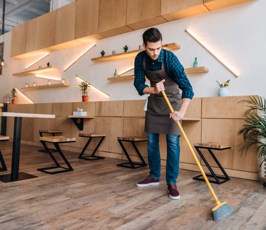 Horvátországban a takarító az egyik legkeresettebb és legjobban fizetett munka idén young worker in apron cleaning floor with sweep in restaurant
