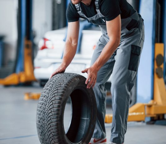Minden tizedik pályaváltó a koronavírus miatt keres új szakmát It's easier to walk that way. Mechanic holds a tire at the repair garage. Replacement of winter and summer tires