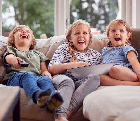 Sokat vesztett lendületéből a Disney streamingoldala Three Children Sitting On Sofa At Home Laughing And Watching TV With Popcorn