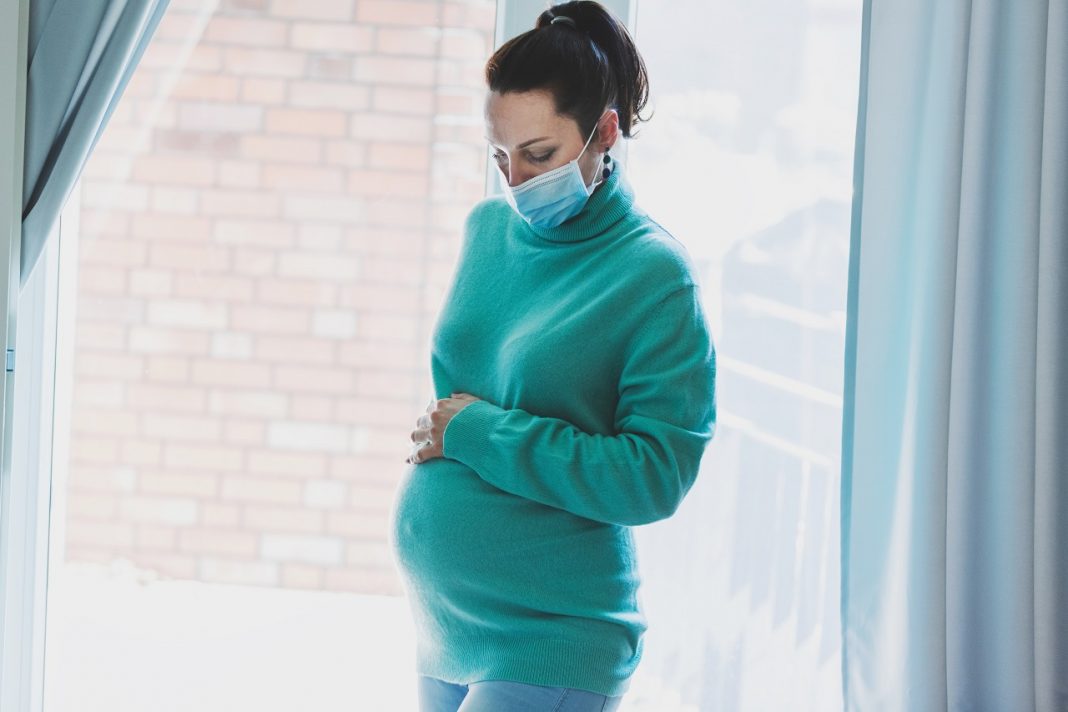 Pregnant woman wearing mask at home