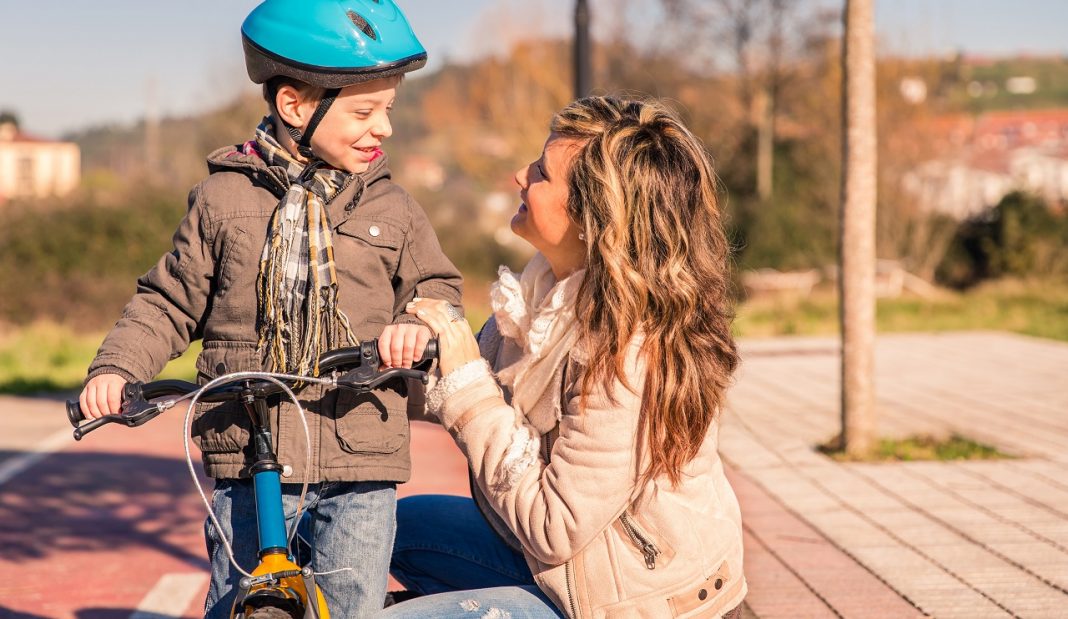 Young woman with child over bicycle on sunny day