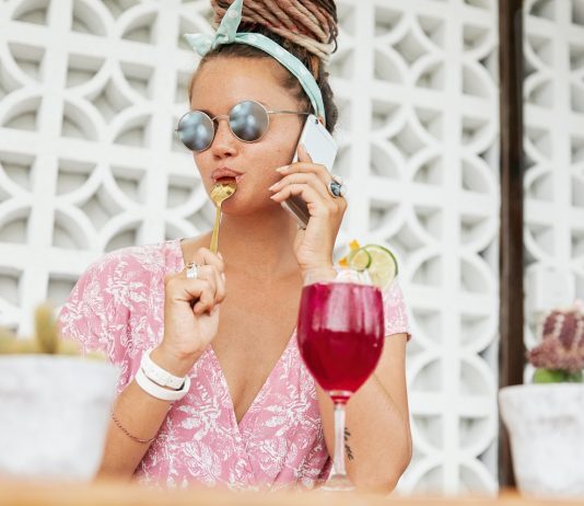 A kulturált együttélés mindennapi kis szabályai, avagy a kiskanál-lenyalás minősített esete Fashionable young woman in trendy eyewear, licks teaspoon as eats something sweet and drinks cocktail or shake, speaks over modern smart phone, shares her impressions of spent holidays abroad
