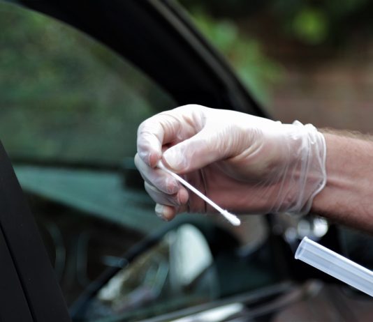 „Jövedelmező, opportunista üzlet…” Hands of NHS worker at mobile coronavirus testing station