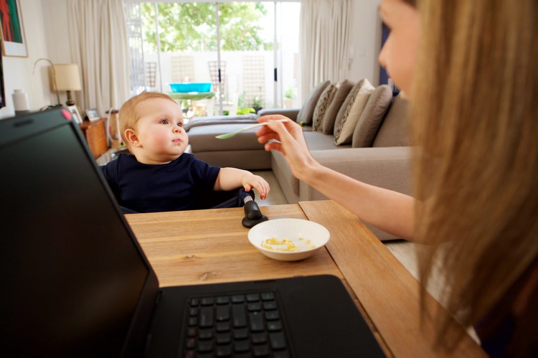 businesswoman working at home and feeding baby