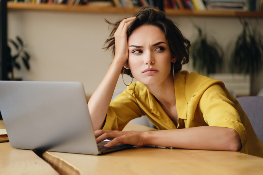 Portrait of young serious businesswoman sitting at the desk tire