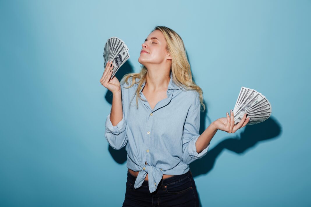 Pretty young amazing blonde woman holding money in hands.